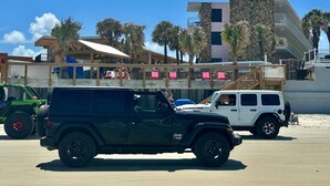 A beachside parking area with a black Jeep and a white Jeep. - Flamingo Inn Beachfront (Daytona Beach Shores)