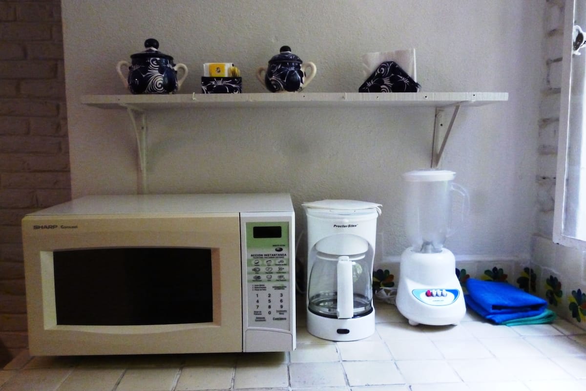 A kitchen with a microwave, coffee maker, and blender on the counter.