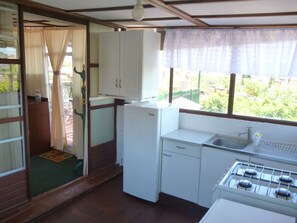 Una cocina compacta con armarios blancos, un refrigerador, un lavaplatos y una estufa.
