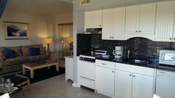 A compact living space with a kitchenette, a sofa, a coffee maker, and a microwave.