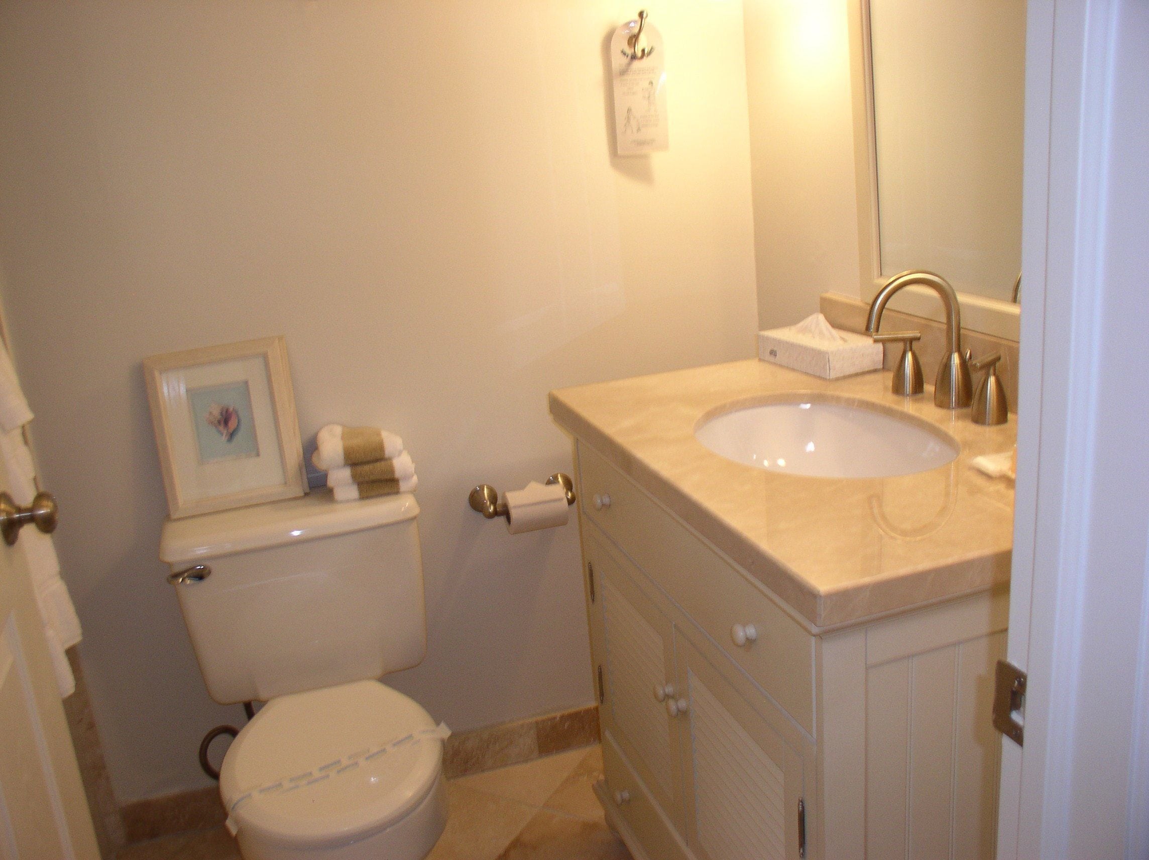 Een badkamer met toilet, wastafel en een foto in een lijst aan de muur.