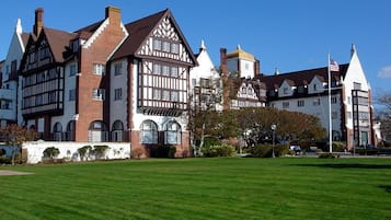 A large, historic building with multiple stories, featuring Tudor-style architecture with white and brown timber framing and steeply pitched roofs.
