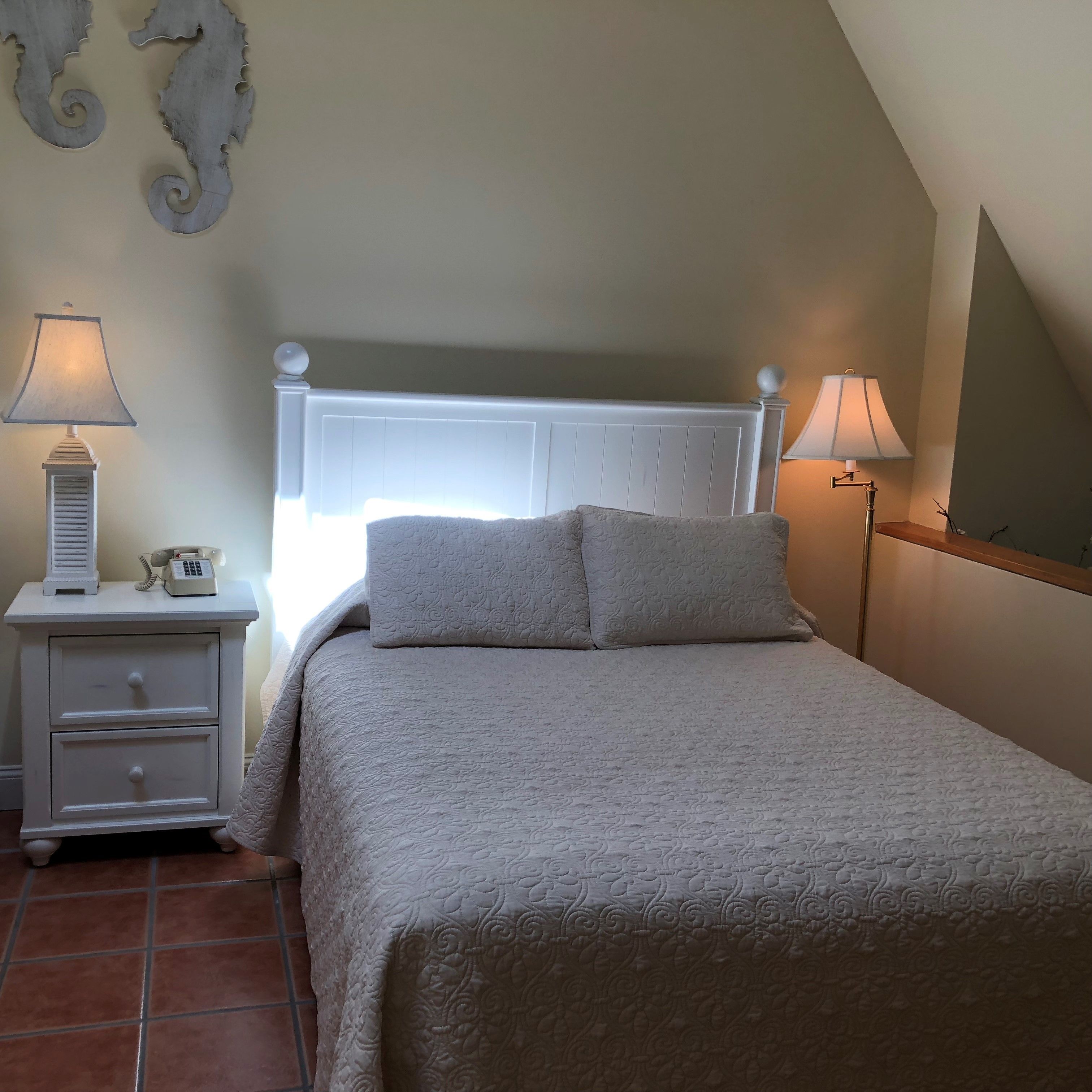 A bedroom with a bed, two bedside tables, a lamp, and a wall-mounted decoration.
