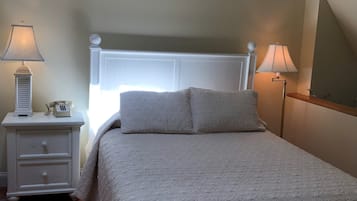 A bedroom with a bed, two bedside tables, a lamp, and a wall-mounted decoration.