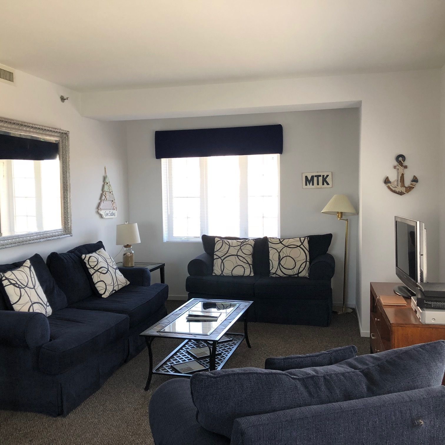 Ein Wohnzimmer mit zwei Sofas, einem Couchtisch, einem Fernseher und einer Lampe.
