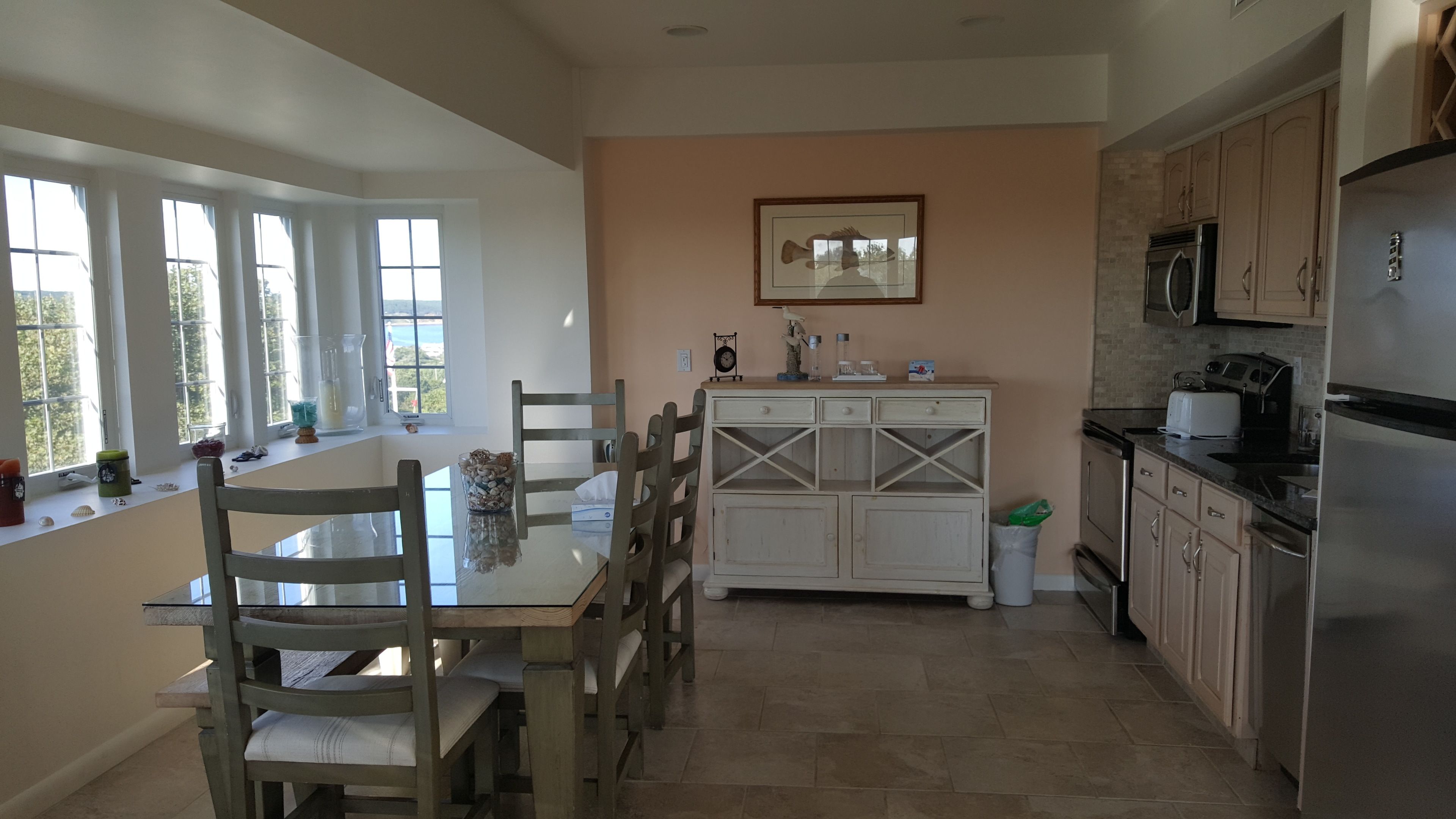 Una cocina con una mesa de comedor, sillas, un armario y un refrigerador.