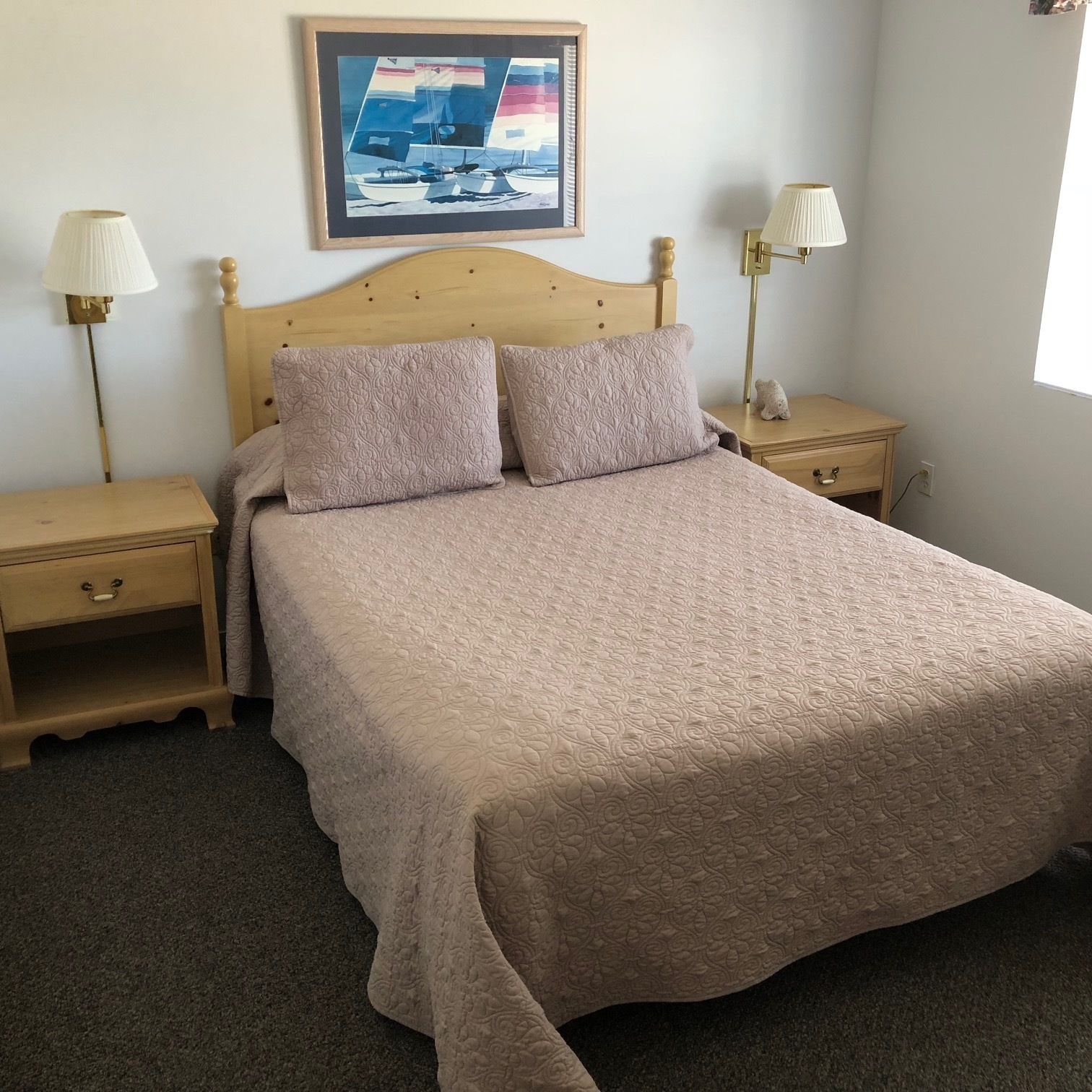 Ein Schlafzimmer mit einem großen Bett, zwei Nachttischen, einer Kopfteil und einem gerahmten Bild an der Wand.