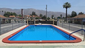 Ein rechteckiger Pool mit roter Umrandung, umgeben von einem Zaun aus Maschendraht.