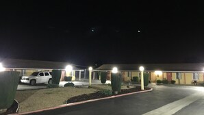 Ein Motel mit Parkplatz, ein weißes Auto parkiert und ein Gebäude mit mehreren Zimmern.