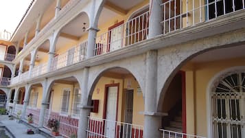 Stunning multi-story building with elegant arches and balconies, each featuring a white railing and a potted plant.