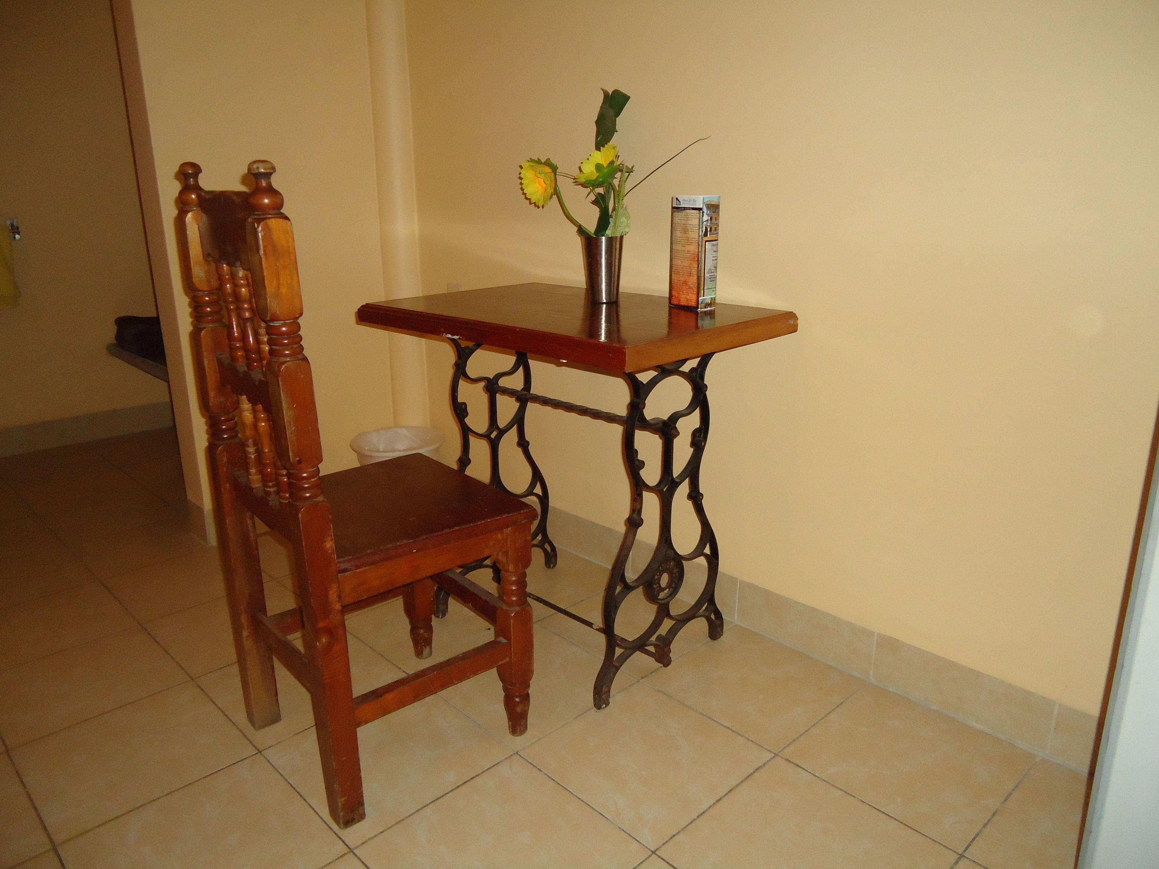A wooden chair and a small table with a vase of flowers.