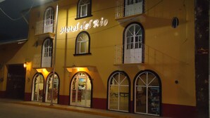 A yellow building with the sign "Hotel del Rio" and multiple arched windows.