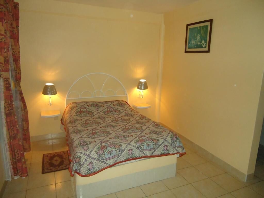 A bedroom with a bed, two bedside lamps, a rug, and a framed picture on the wall.