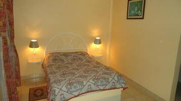 A bedroom with a bed, two bedside lamps, a rug, and a framed picture on the wall.