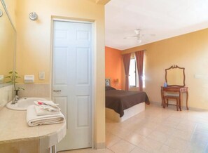 A bedroom with a bed, a bedside table, a mirror, and a chair.