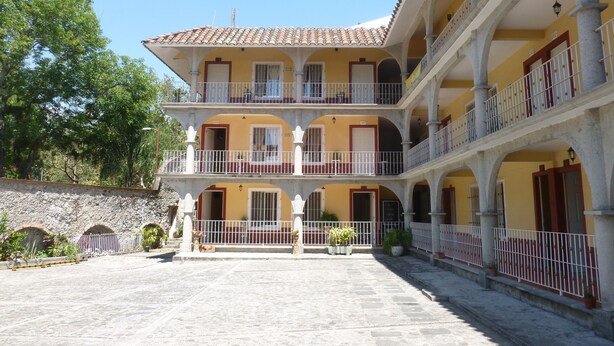 A multi-story building with balconies, a courtyard, and a stone wall.