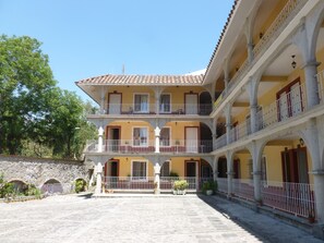 A multi-story building with balconies, a courtyard, and a stone wall.