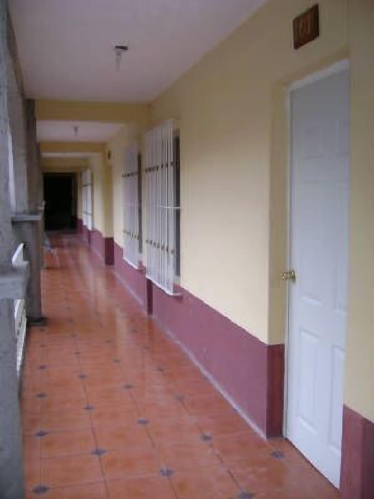 A corridor with tiled flooring, a white door, and a window with bars.