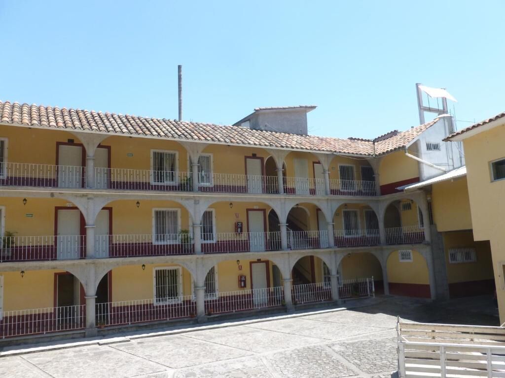 Un edificio amarillo con techo de tejas y varios balcones.