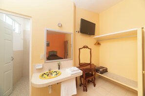 A bathroom with a sink, mirror, television, shower, and a chair.