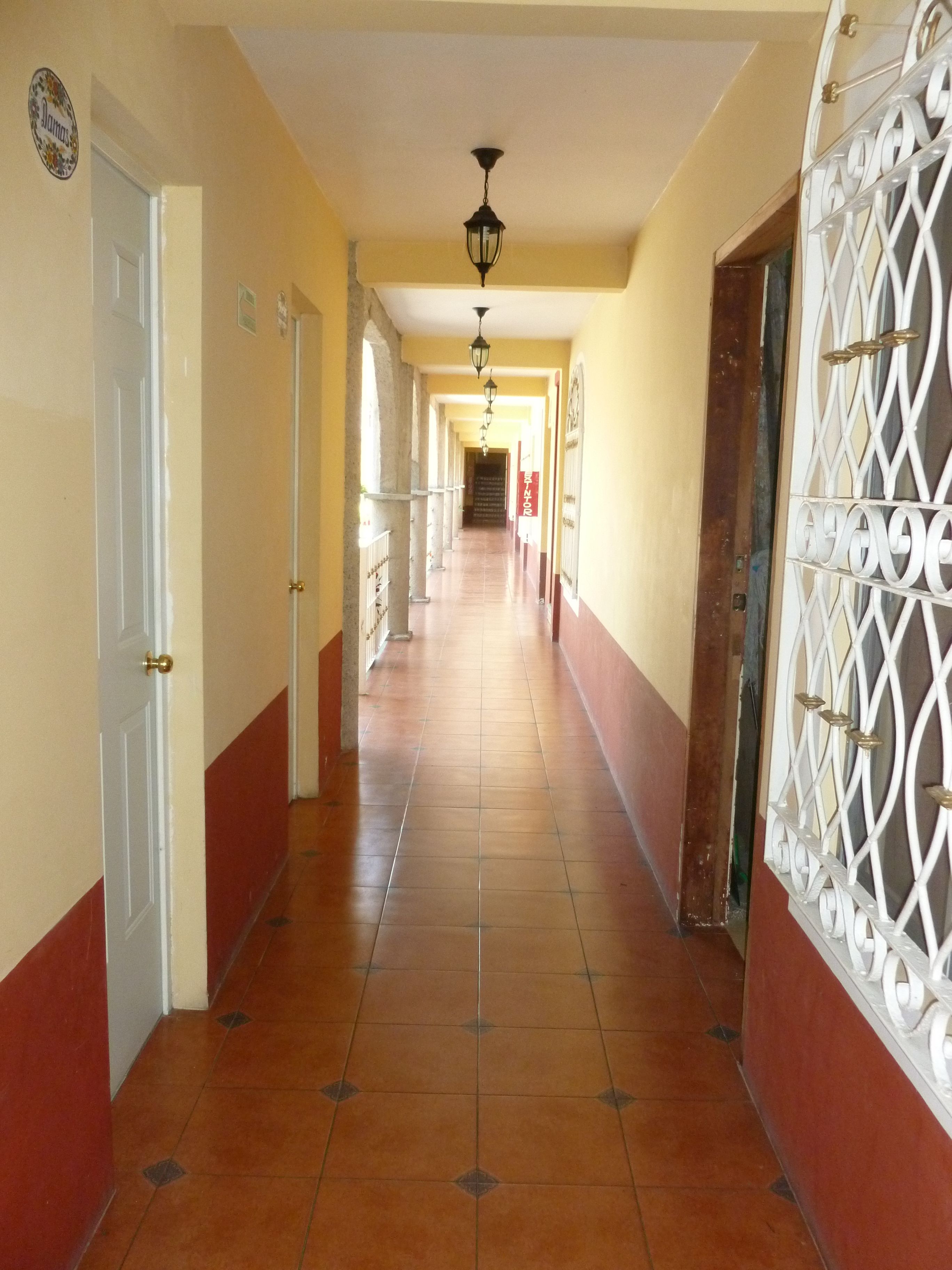 Un passadís amb sòl de rajoles, portes blanques i una reixa metàl·lica decorativa.