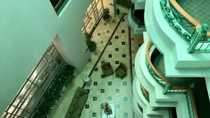 A multi-level atrium with a central open space, surrounded by balconies with green railings and wooden balustrades.