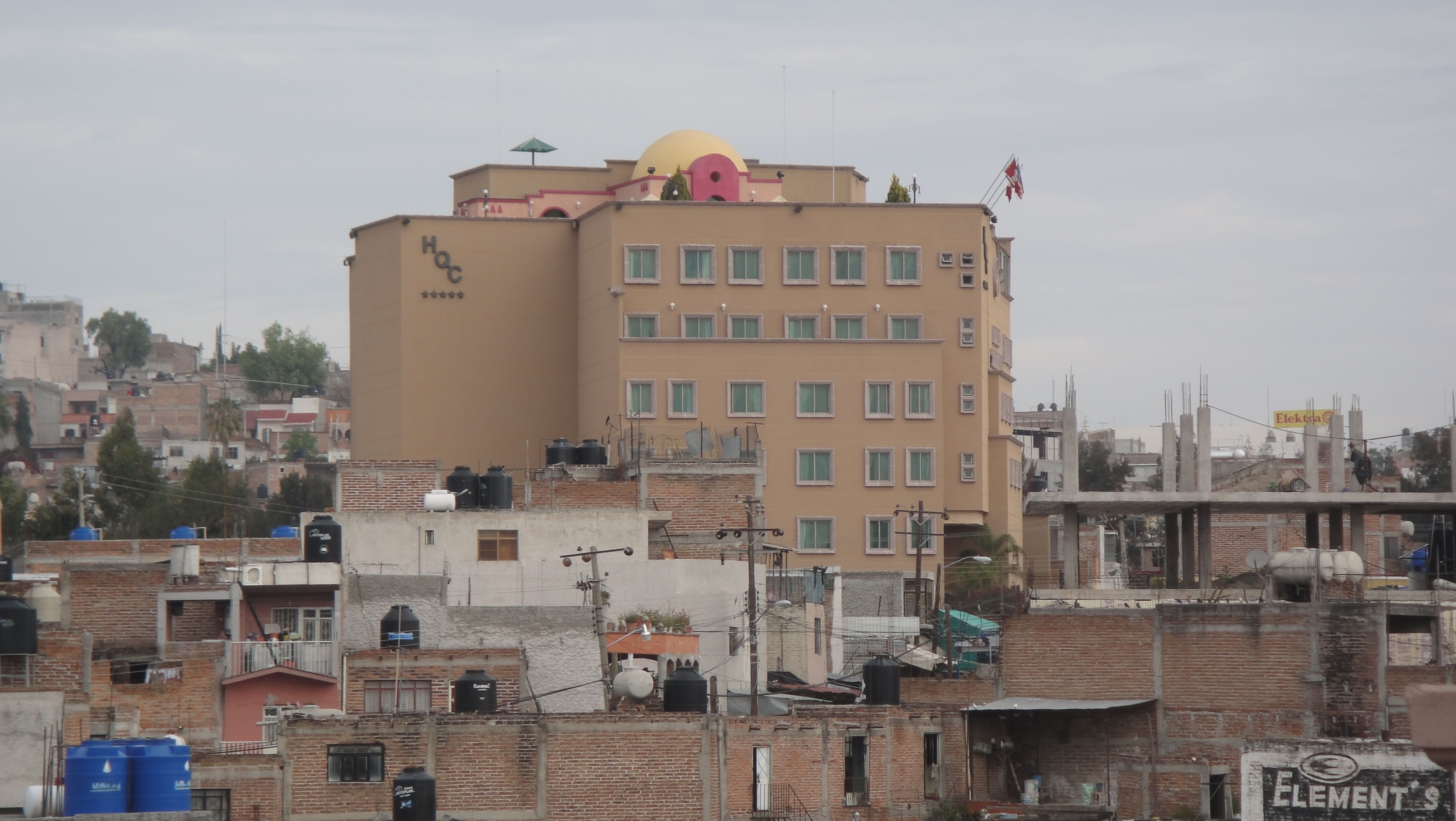 A multi-story building with a flat roof, several windows, and a large water tank on the roof.