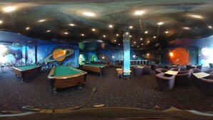 A pool hall with multiple pool tables, seating areas, and a space-themed mural on the walls.