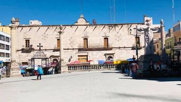 A plaza with a large open space, a statue, and a building with classical architecture.