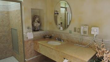 Une salle de bain avec un lavabo en marbre, un miroir, un téléphone et un espace douche.