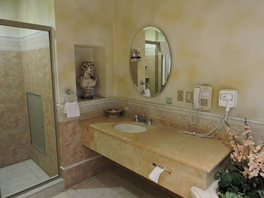 Une salle de bain avec un lavabo en marbre, un miroir, un téléphone et un espace douche.