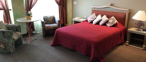 Une chambre d’hôtel avec un grand lit, une chaise, une petite table et une lampe.