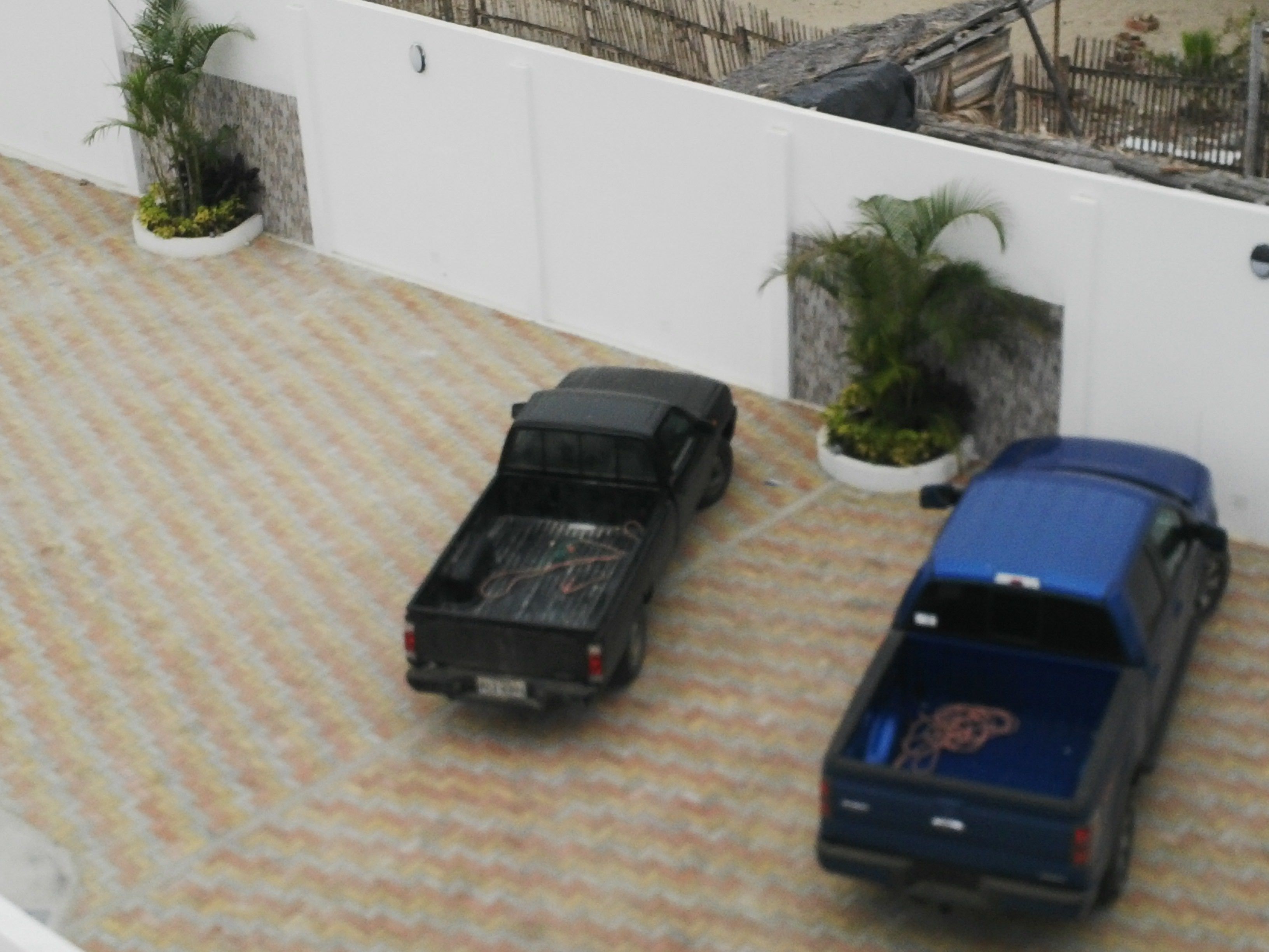 A model of a parking area with two toy cars and potted plants.