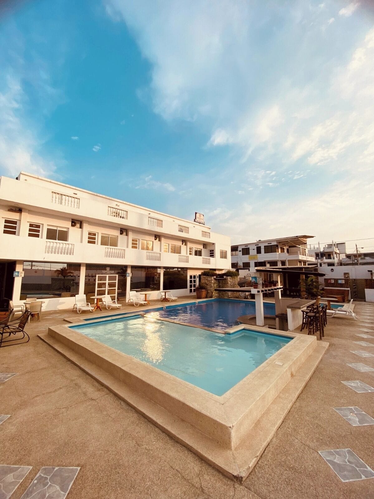 A hotel with a swimming pool, outdoor seating, and a terrace.