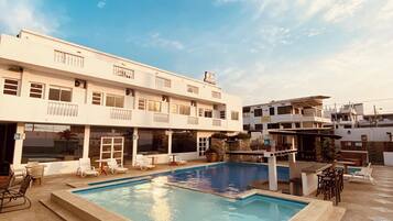 A hotel with a swimming pool, outdoor seating, and a terrace.