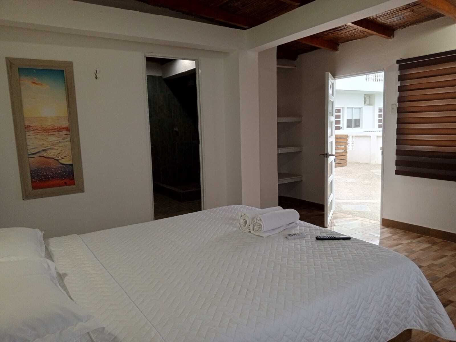 A bedroom with a bed, a painting, a closet, and a view of the outside.
