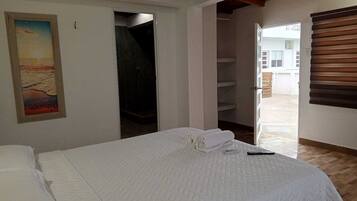 A bedroom with a bed, a painting, a closet, and a view of the outside.