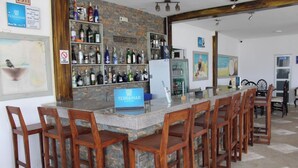 A bar area with a stone counter, wooden chairs, and a sign for Terramar Hotels. - Terramar Hoteles  (Crucita)