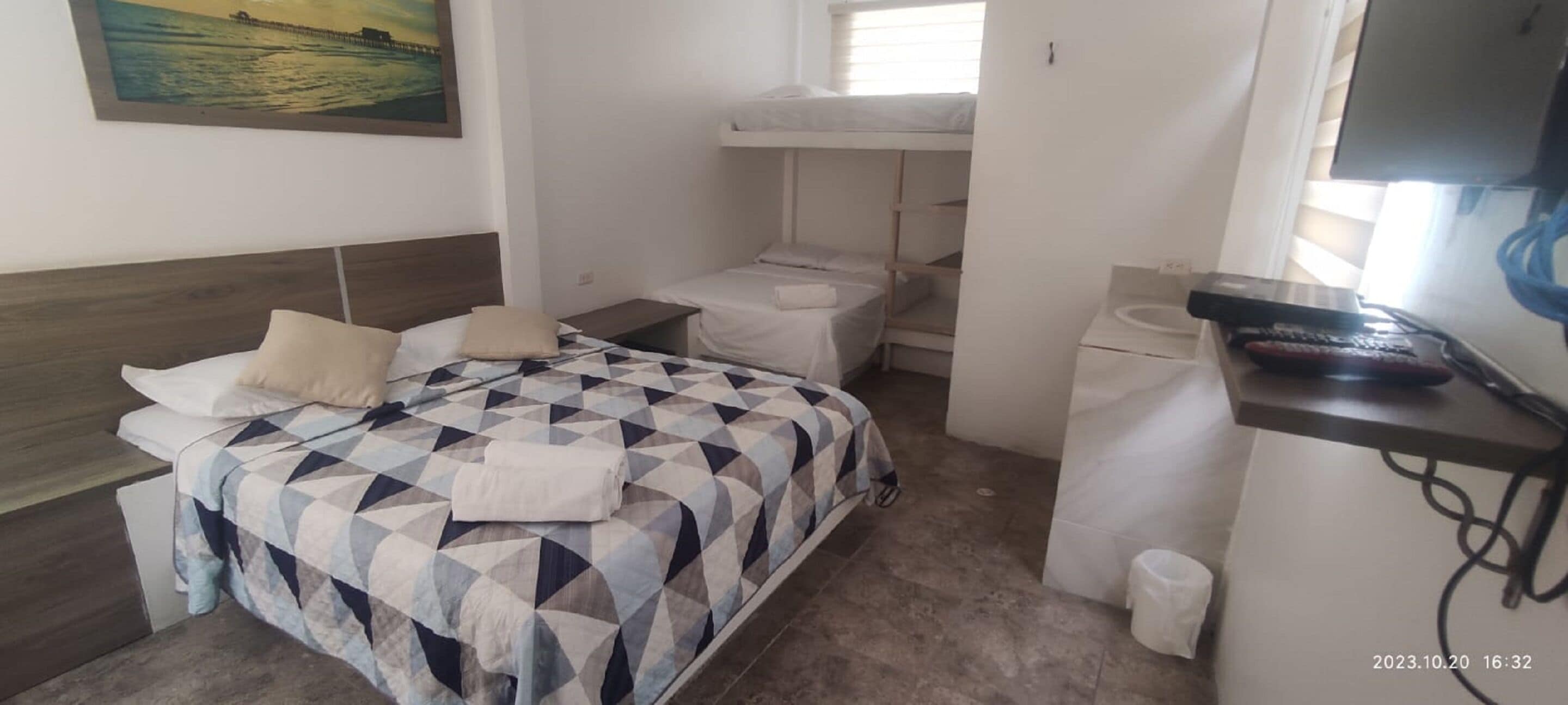 Un dormitorio con cama, literas, escritorio, silla, televisor y baño.