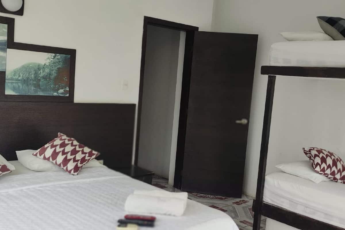 A hotel room with a bed, a bunk bed, and a door.