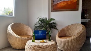 A room with two wicker chairs, a small table with a sign for Terramar Hotels, and a potted plant. - Terramar Hoteles  (Crucita)