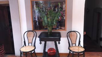 Una habitación con dos sillas de mimbre, una mesa negra y una planta en maceta.