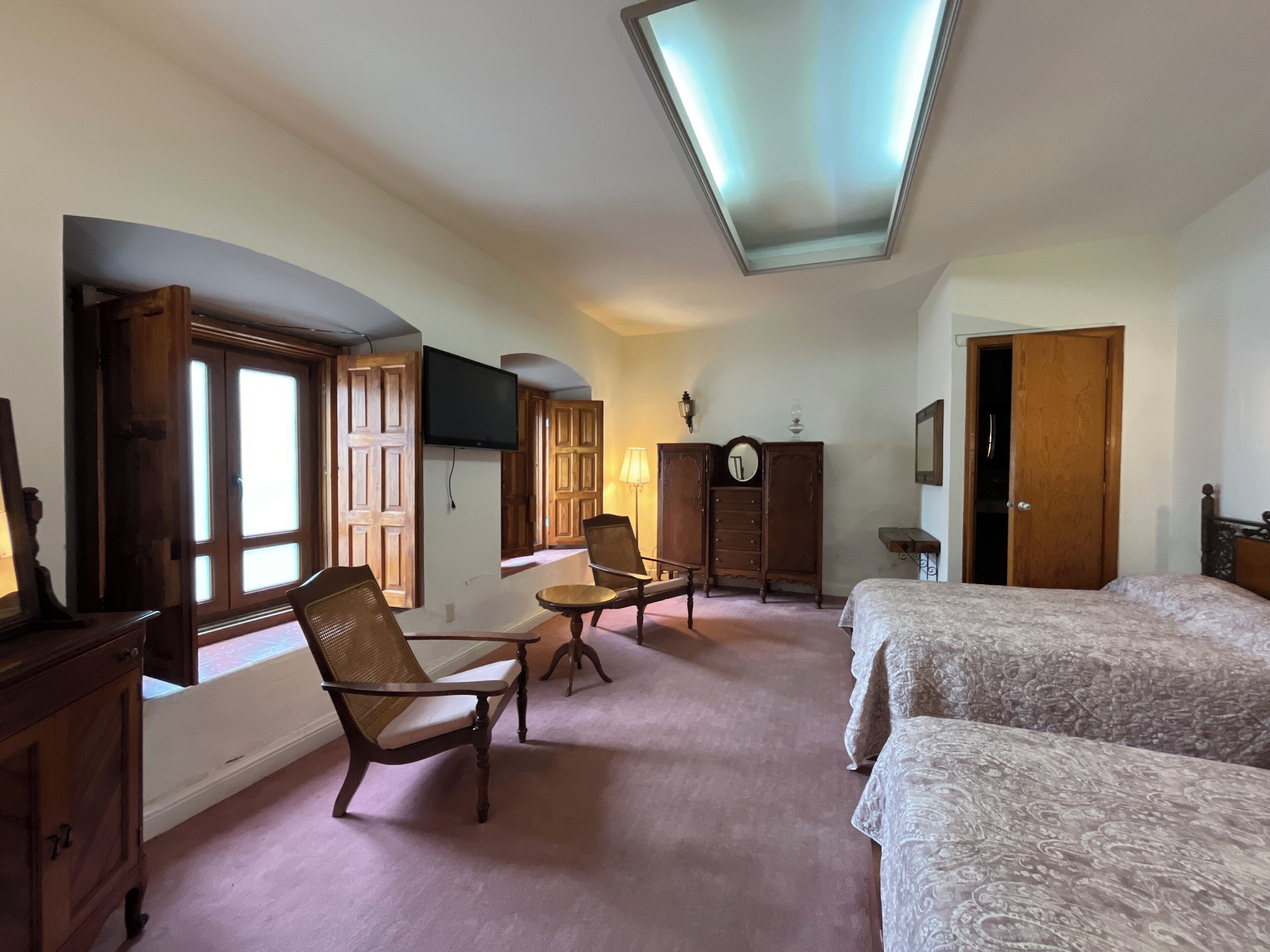 Ein Schlafzimmer mit zwei Betten, einem Holzschrank, einem Sessel und einem Fernseher.