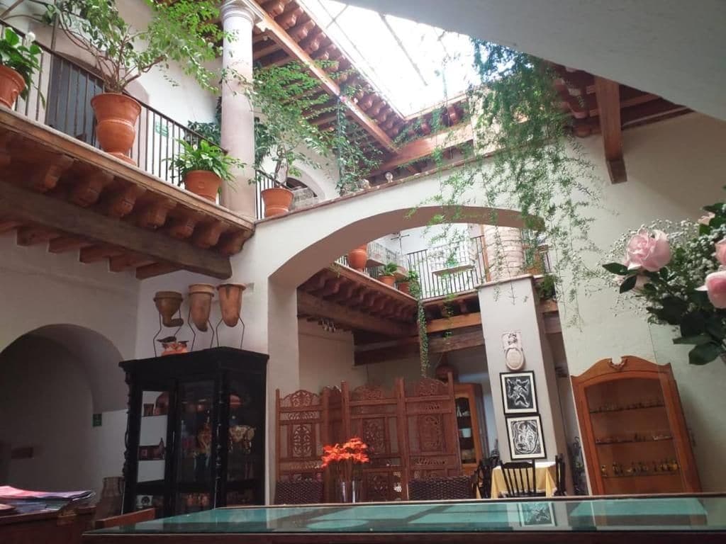 Un patio con una mesa de vidrio, plantas en macetas y un mueble de madera.