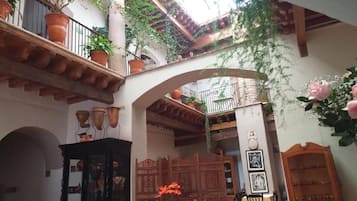 Un patio con una mesa de vidrio, plantas en macetas y un mueble de madera.