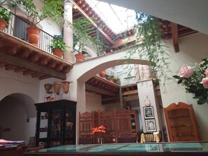 A courtyard with a glass table, potted plants, and a wooden cabinet. - Casa del Pingorongo (Zacatecas)