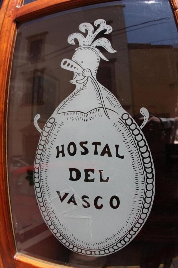A window with a decorative emblem featuring a stylized rooster and the text "HOSTAL DEL VASCO". - Casa del Pingorongo (Zacatecas)
