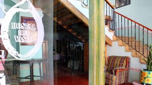A hotel entrance with a staircase, a striped armchair, and a potted plant. - Casa del Pingorongo (Zacatecas)