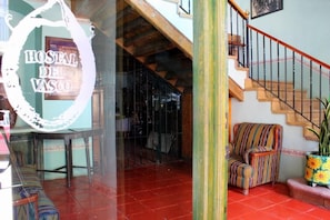 A hotel entrance with a staircase, a striped armchair, and a potted plant. - Casa del Pingorongo (Zacatecas)