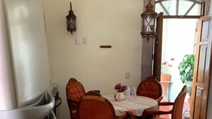 A dining area with a wooden table and chairs, a refrigerator, and a hanging light fixture. - Casa del Pingorongo (Zacatecas)